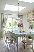 Dining table and chairs with open door to garden below skylight in Hampshire home UK