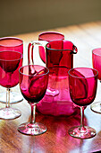 Red wine glasses and jug on wooden sideboard in Hampshire home UK