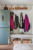 Baskets on shelf above coats and scarves with open front door in Hampshire home UK