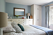 Double bed with storage cupboards and rectangular mirror in Hampshire home UK