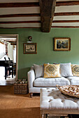 Sofa and ottoman in beamed living room of 17th century Northamptonshire cottage UK