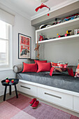 Red cushions and toys with grey single daybed in North London home UK