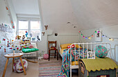 Festoon lights and toys with metal framed bed in girls' room Grade II listed Hampshire cottage UJ