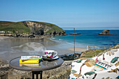 Upholstered chair and table on balcony terrace with view of beach at low tide Cornwall UK