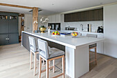 Orchid on kitchen unit with bar stools in open plan Hampshire home UK