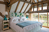Turquoise lamps with blue blanket on double bed in Hampshire barn conversion UK