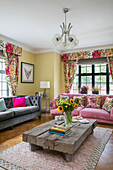 Pink and grey sofas with low wooden coffee table in modernised 1900s Arts and Crafts style London home UK