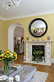Convex mirror with cut flowers in modernised 1900s Arts and Crafts style London home UK