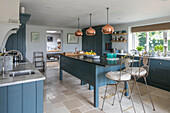 Metal bar stools in teal fitted kitchen of Oxfordshire home UK