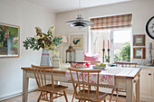 Holzstühle am Tisch mit Hängelampe und Schnittblumen in einem Haus in Kent, UK