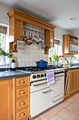 Blaue Kasserolle auf Herdplatte in Holzküche mit Pfannen- und Tellerregalen Kent UK