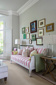Fotowand und rosa-weiß gestreiftes Sofa in einem Londoner Wohnzimmer UK