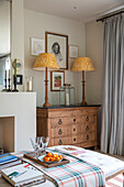 Pair of yellow lamps on wooden chest of drawers in London living room UK