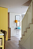 Gelbe Lampe und türkisfarbene Handtasche auf einem Demi-Lune-Dielentisch in einem Haus in London, UK