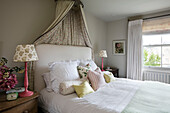 Ein Paar Lampen und ein Bett mit Baldachin am Fenster in einem Londoner Haus UK