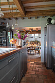 Galley style kitchen with salvaged terracotta floor tiles and beamed ceiling in Norfolk cottage England UK
