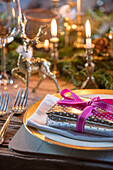 Christmas present on place setting with lit candles and silverware in Norfolk cottage England UK