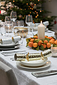 Christmas crackers and lit candles with scented oranges on dining table in Hampshire home UK