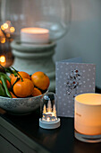 Bowl of satsumas and lit candles with Christmas card in Hampshire home UK