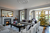Lit Christmas tree in window of classic living room in Hampshire home UK