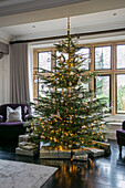In Geschenkpapier verpackte Geschenke unter einem großen Weihnachtsbaum in einem Haus in Hampshire, UK