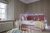 Gedämpftes rosa Bett mit Lichterketten und Kuscheltieren in einer Wohnung in Hampshire, UK