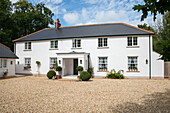 Gravel driveway entrance and white facade of detached Sussex home UK