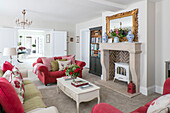 Gilt framed mirror on fireplace with red sofas in Sussex living room UK