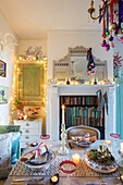 Beleuchtete Kerzen und Weihnachtskugeln mit Bücherregal im Kamin eines Hauses in Norwich Norfolk UK