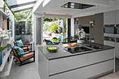 Open plan kitchen extension with retro style chairs and garden view in London home UK