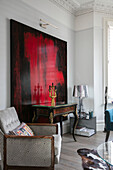 Large art canvas with vintage table and geometric armchair in London home UK