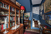 Antique bookcase and framed art in hallway of Sussex home