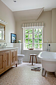 Freestanding bath with wooden wash stand in bathroom painted Slaked Lime Victorian coach house West Sussex UK