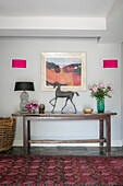 Equestrian statue on wooden hall table with pink wall lights in Hampshire home England UK