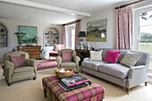 Light grey sofa with beige armchairs and tartan ottoman in Hampshire living room England UK