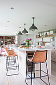 Industrielle Hängeleuchten und Retro-Barhocker in einer Küche aus gekalkter Eiche in einem Bauernhaus in Surrey UK