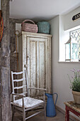 Körbe auf einem alten französischen Schrank mit Stuhl am Fenster in einem Bauernhaus in Surrey UK