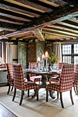 Candles on dining table with red checked chairs and folding screen in Kent farmhouse UK