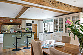 Hellgrüne Barhocker mit Holztisch in einer offenen Küche in einem Bauernhaus in Kent, UK