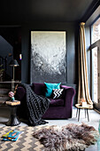 Leinwand und violetter Sessel im Wohnzimmer mit schwarz gestrichenen Wänden und Decken in einer umgebauten walisischen Scheune, UK
