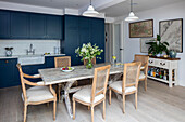 Tisch aus alten Gerüstbohlen mit blauen Schränken und antiken Landkarten in der Küche einer Wohnung im Norden Londons UK