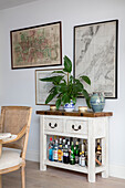 Framed antique maps above butcher?s block used as drinks stand in North London apartment UK