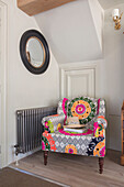 Tropical Aztec Maharaja Chair with round mirror radiator from screwfix in1840s Cotswolds cottage Oxfordshire UK