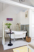 Slipper bath and Kaleidoscope tiles with lilies on black side table in 1840s Cotswolds cottage Oxfordshire UK