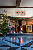 Weihnachtsbaum und Holzofen mit sternförmig bemalten Dielen Norfolk-Bauernhaus UK