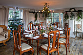 Antique terracotta brick floor with Christmas foliage on Christmas dining table in former dairy of Norfolk farmhouse UK