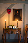 Angezündete Kerze auf antikem Holztisch mit Wänden aus Eisschollen und Balken in einem Bauernhaus in Duck Egg, Norfolk, UK