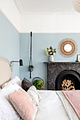 Pastel blues and pinks in bedroom with Sunburst rattan mirror Victorian family home Manchester UK