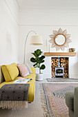 Sunburst mirror and faded yellow retro style sofa in Victorian family home Manchester UK