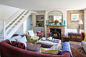 Open plan living room with staircase and lit woodburner walls in Pointing Victorian cottage Midhurst West Sussex UK